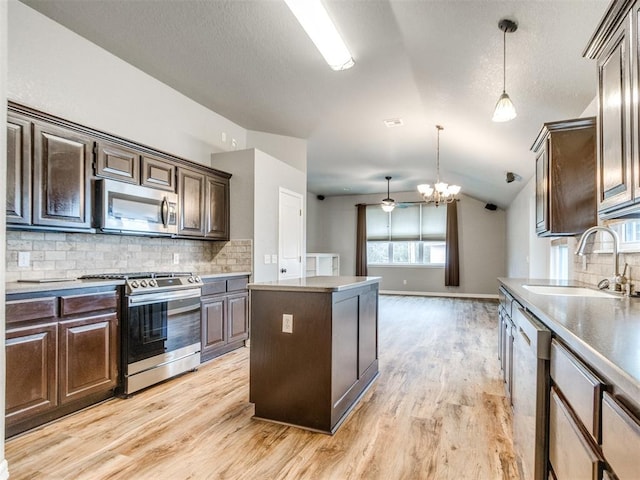 kitchen featuring sink, vaulted ceiling, hanging light fixtures, appliances with stainless steel finishes, and a kitchen island