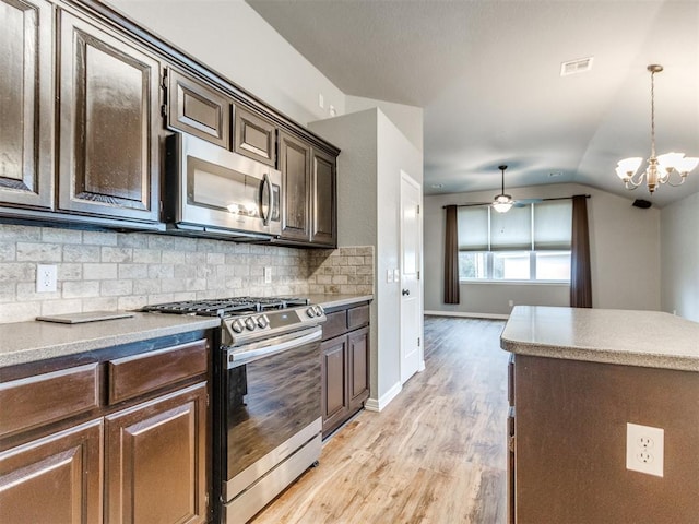 kitchen featuring light hardwood / wood-style flooring, appliances with stainless steel finishes, dark brown cabinets, tasteful backsplash, and decorative light fixtures