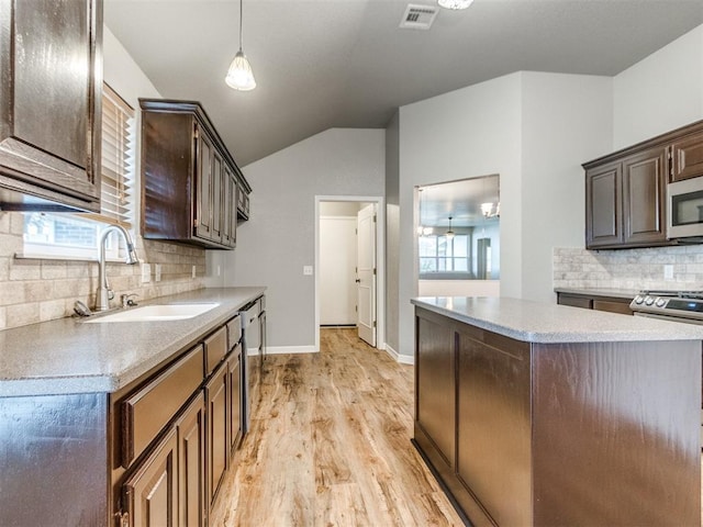 kitchen featuring vaulted ceiling, pendant lighting, sink, stainless steel appliances, and dark brown cabinets