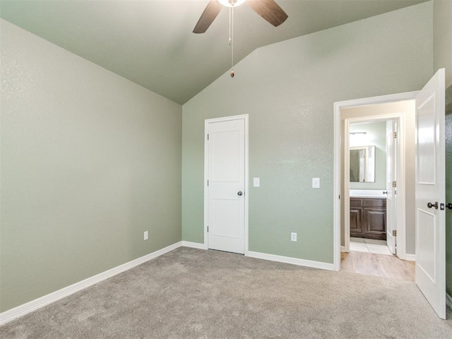 unfurnished bedroom with lofted ceiling, ensuite bath, light colored carpet, and ceiling fan