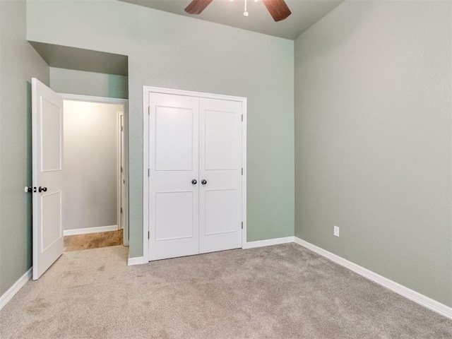 unfurnished bedroom featuring ceiling fan, light colored carpet, and a closet