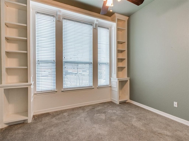 carpeted spare room with ceiling fan and built in shelves