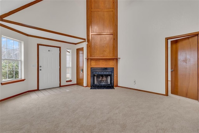 unfurnished living room with crown molding, a towering ceiling, light colored carpet, and a fireplace