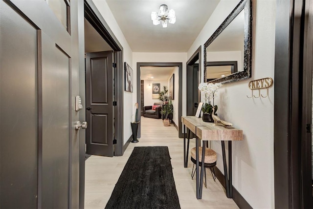 corridor with an inviting chandelier and light hardwood / wood-style flooring