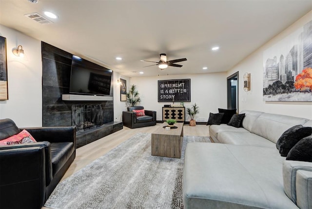 living room with wood-type flooring, a fireplace, and ceiling fan