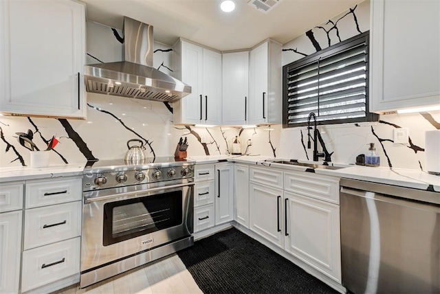 kitchen featuring appliances with stainless steel finishes, white cabinetry, sink, exhaust hood, and light stone counters