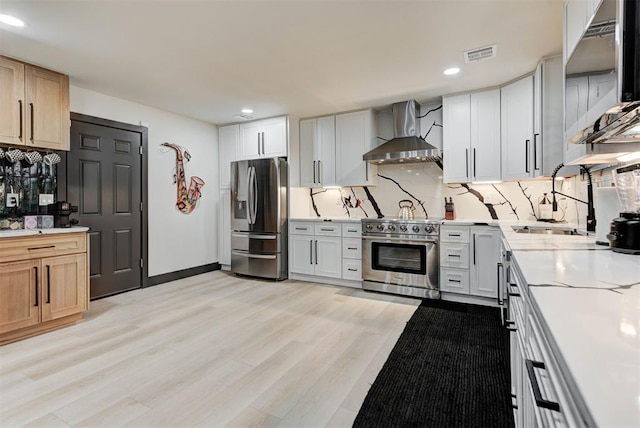 kitchen with white cabinetry, sink, stainless steel appliances, and wall chimney exhaust hood