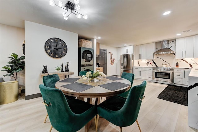 dining space with stacked washer and clothes dryer and light hardwood / wood-style floors