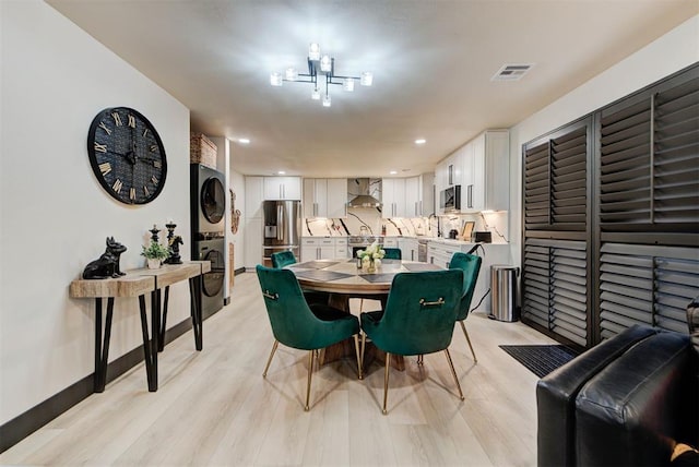 dining area with stacked washer / dryer, sink, and light hardwood / wood-style flooring