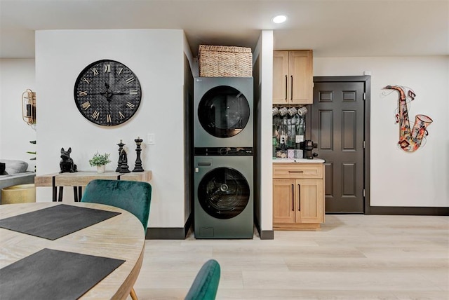 laundry area featuring stacked washer and clothes dryer and light hardwood / wood-style floors