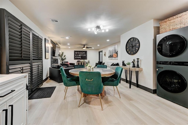 dining area with light wood-type flooring, ceiling fan, and stacked washing maching and dryer