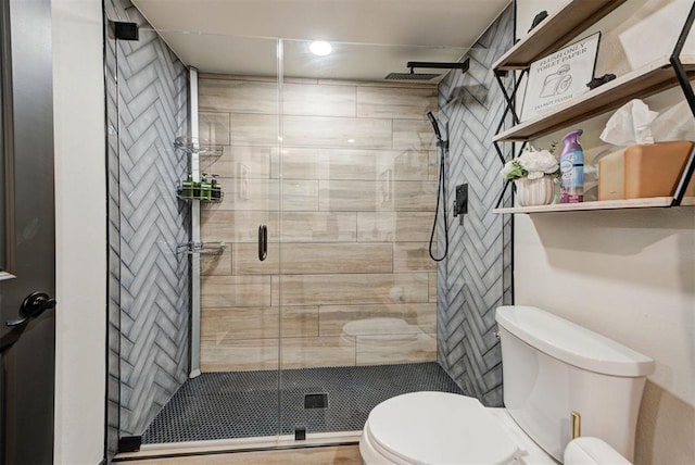 bathroom with a shower with shower door and toilet