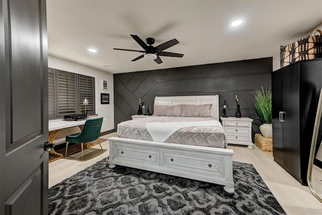 bedroom with light hardwood / wood-style floors, ceiling fan, and wood walls