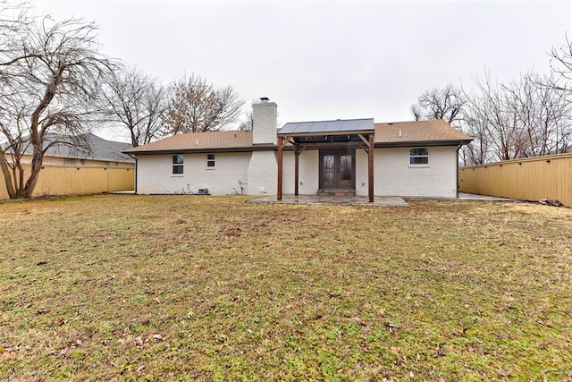 rear view of house featuring a lawn, a patio, and french doors