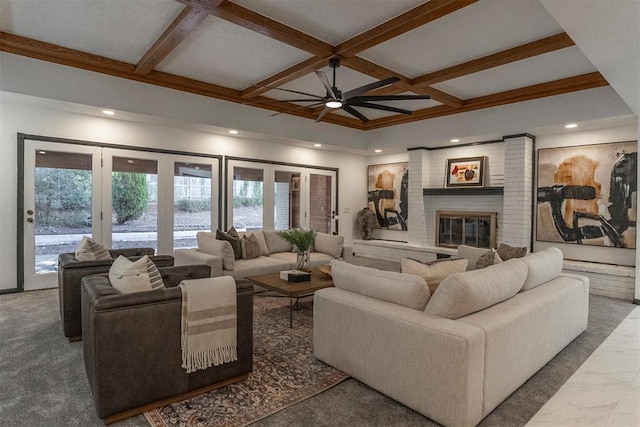 living room with beamed ceiling, ceiling fan, coffered ceiling, and a fireplace