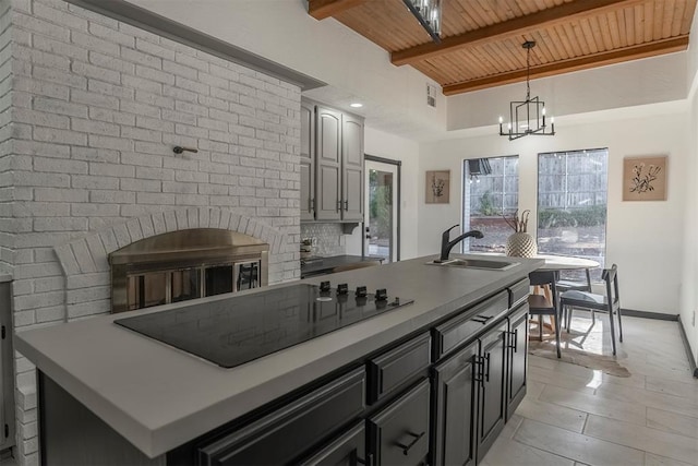 kitchen with pendant lighting, sink, wood ceiling, black electric stovetop, and an island with sink