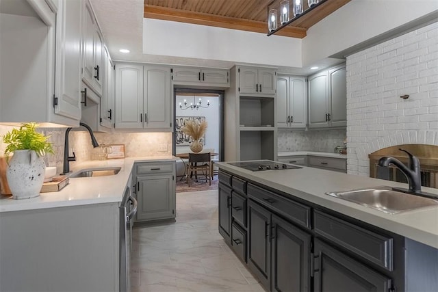 kitchen with gray cabinetry, sink, tasteful backsplash, and black electric stovetop