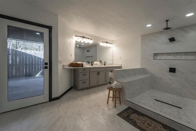 bathroom featuring vanity, a textured ceiling, and a tile shower