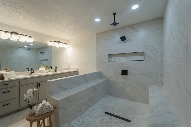 bathroom featuring vanity, a textured ceiling, and a tile shower