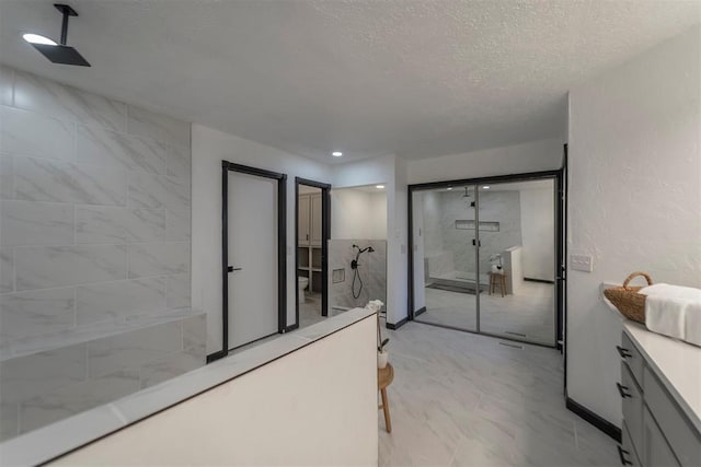 bathroom with vanity, a textured ceiling, and a tile shower