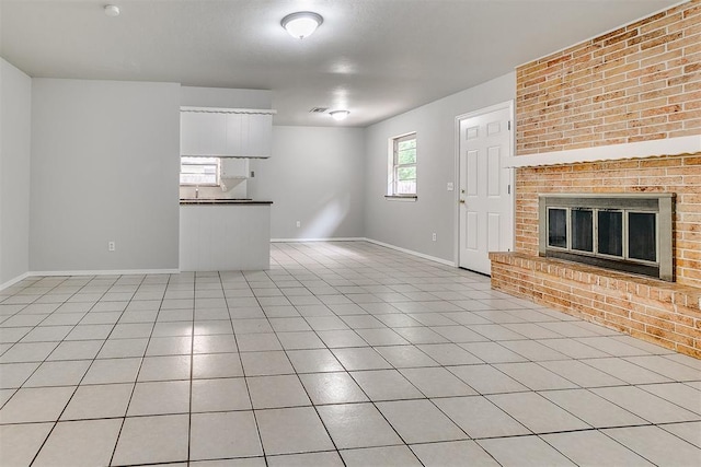 unfurnished living room with light tile patterned floors, baseboards, and a fireplace