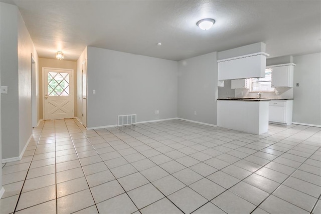 unfurnished living room featuring visible vents, plenty of natural light, and light tile patterned floors