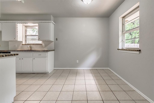 kitchen with a sink, dark countertops, backsplash, and white cabinetry