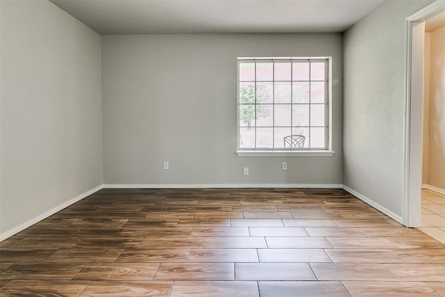 unfurnished room with baseboards and wood finish floors