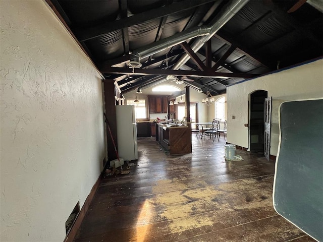 hall with vaulted ceiling, dark hardwood / wood-style floors, and a chandelier