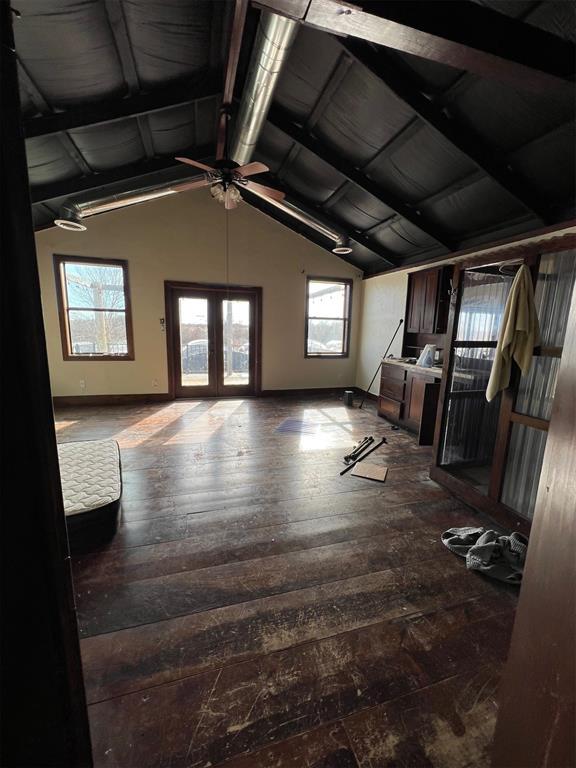 unfurnished living room with dark hardwood / wood-style flooring, lofted ceiling with beams, french doors, and ceiling fan