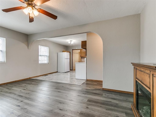 unfurnished living room featuring washer / clothes dryer, hardwood / wood-style floors, and ceiling fan