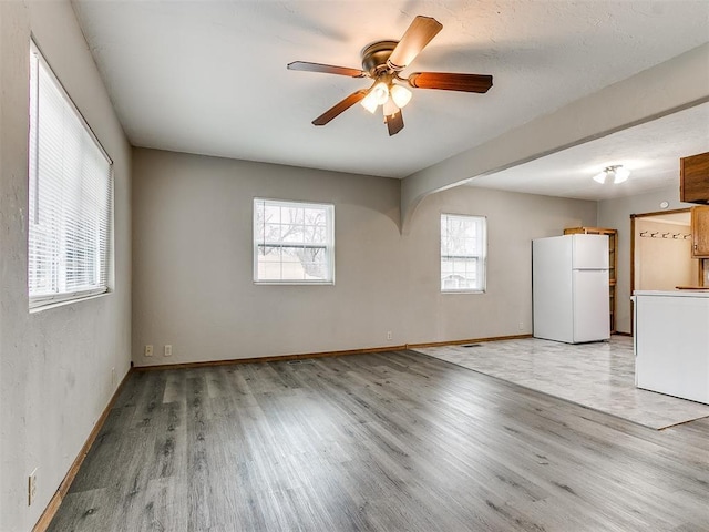 spare room with ceiling fan and light wood-type flooring