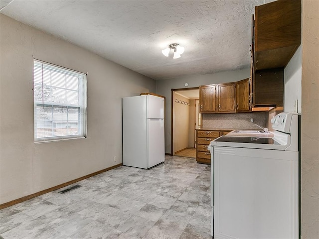 kitchen with sink, white refrigerator, tasteful backsplash, a textured ceiling, and washer / dryer