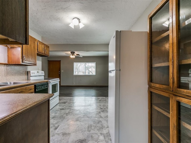 kitchen featuring sink, white appliances, a textured ceiling, and ceiling fan