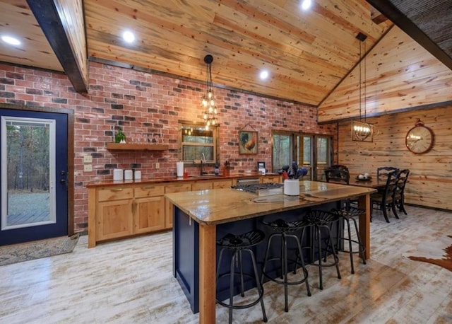 kitchen with sink, hanging light fixtures, light stone countertops, wooden ceiling, and light hardwood / wood-style flooring