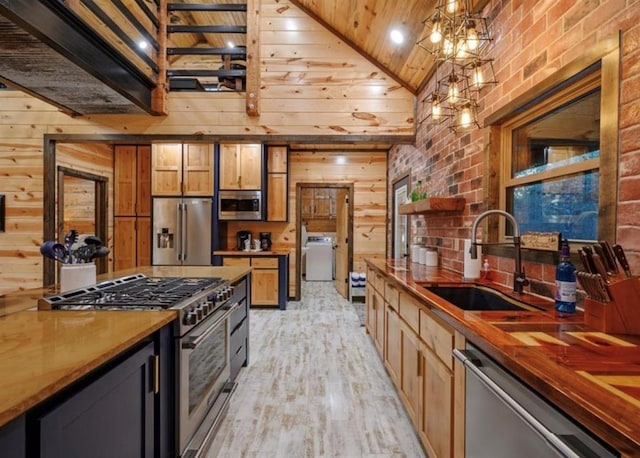 kitchen with sink, wood walls, decorative light fixtures, wooden ceiling, and stainless steel appliances