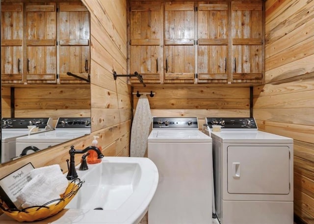 washroom featuring washer and dryer, sink, and wood walls