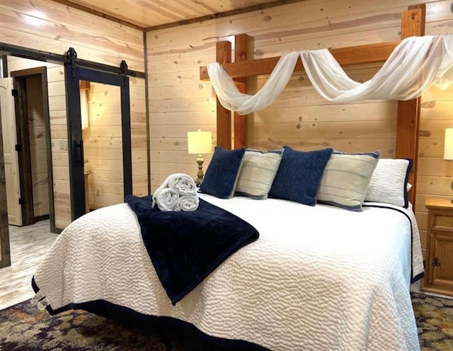 bedroom with hardwood / wood-style floors, wooden ceiling, a barn door, and wood walls