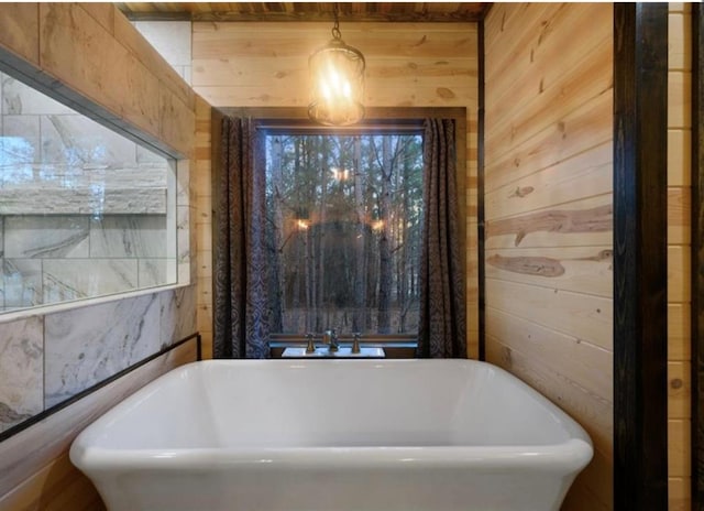 bathroom featuring a washtub and wooden walls