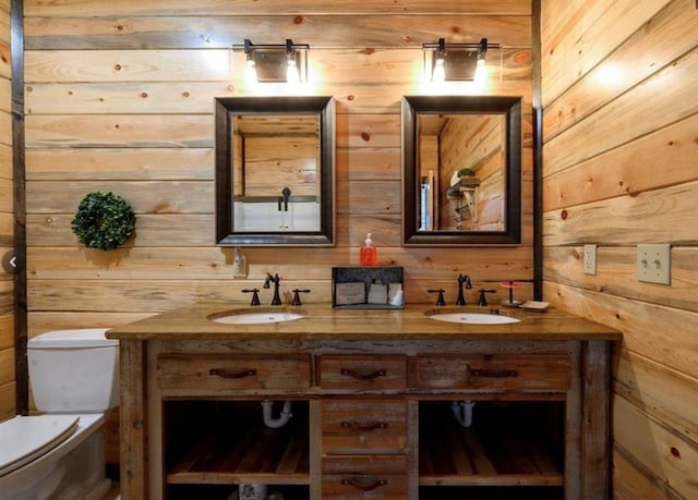 bathroom featuring vanity, wooden walls, and toilet