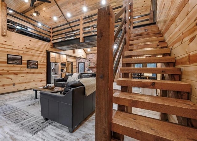 living room featuring wooden ceiling, a high ceiling, light hardwood / wood-style flooring, and wood walls