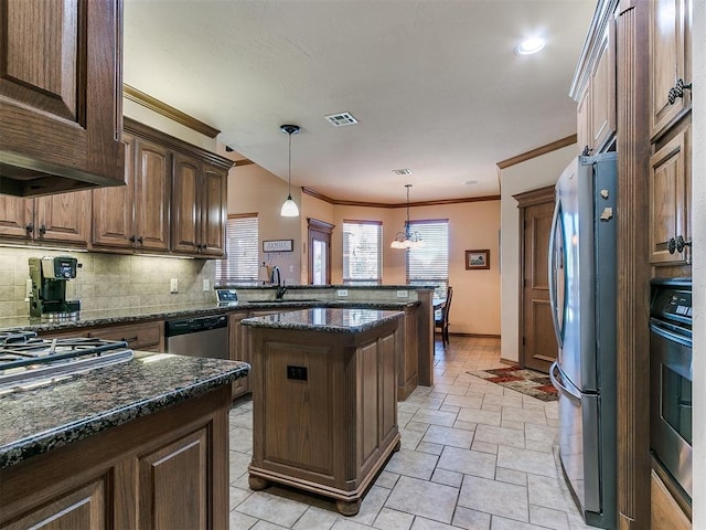 kitchen featuring a kitchen island, decorative light fixtures, sink, dark stone countertops, and stainless steel appliances