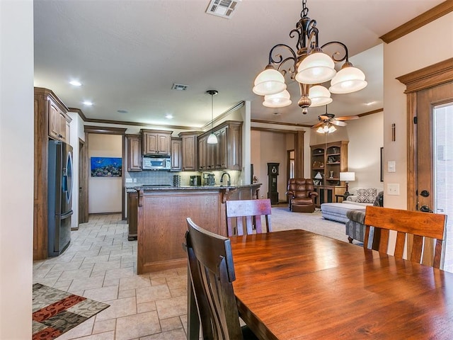 dining area with crown molding and ceiling fan with notable chandelier