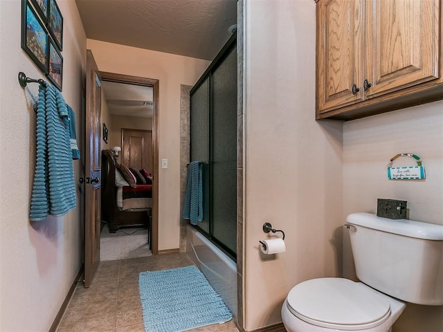 bathroom with tile patterned flooring, shower / bath combination with glass door, and toilet