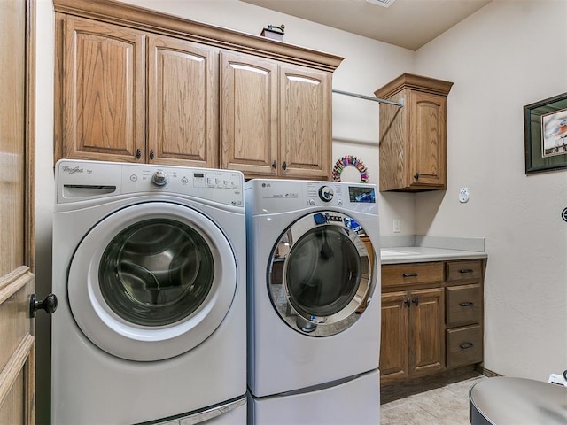 washroom with cabinets, washing machine and clothes dryer, and light tile patterned flooring