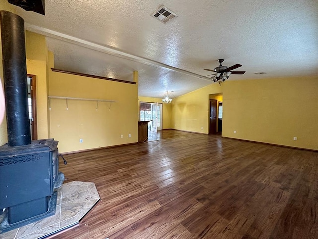 living room featuring a wood stove, visible vents, vaulted ceiling, and wood finished floors