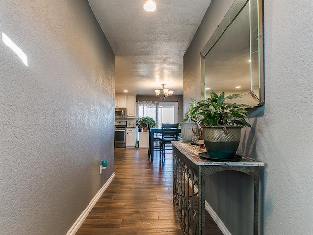 hallway featuring dark wood-type flooring and a chandelier