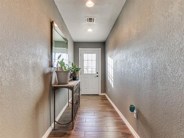 doorway to outside with dark wood-type flooring and a textured ceiling