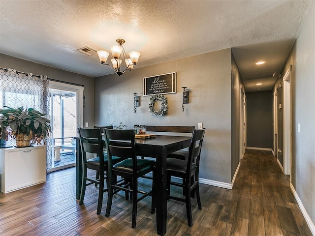 dining area with dark hardwood / wood-style floors, a textured ceiling, and a chandelier