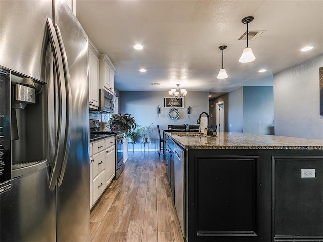 kitchen featuring sink, appliances with stainless steel finishes, a kitchen island with sink, white cabinetry, and hanging light fixtures